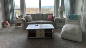 Un salon avec un canapé, un fauteuil, une table basse et une vue sur la plage.