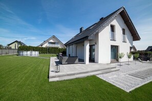 Une maison moderne à deux étages, dotée d’un patio, d’une piscine et d’une pelouse bien entretenue.