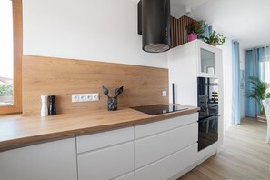 Une cuisine moderne dotée d’un plan de travail en bois, de meubles blancs, d’une hotte noire et offrant une vue sur l’espace repas.