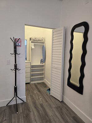 A walk-in closet with a mirrored closet rod, a 'No Smoking' sign, and a patterned throw on the shelves. - La cienfuegera suite 1 (Tampa)