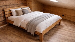 A wooden bed in a room with sloped ceilings and wooden walls. - Delightful 3-bedroom apartment in charming Frutigen awaits you (Frutigen)