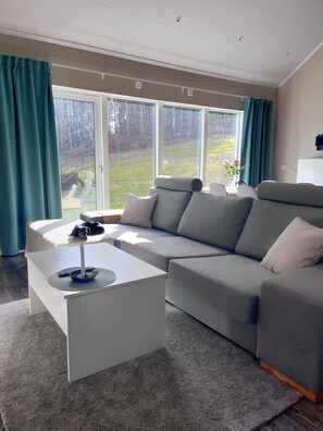 A modern living room with a grey sofa, a white coffee table, and a large window with curtains. - Country House on a Horse Farm - Dogs welcome and you can rent horses. (Veddige)