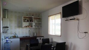 Une cuisine compacte avec un coin repas, un distributeur d’eau et un téléviseur fixé au mur.