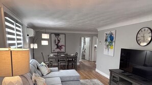 Una sala de estar con sofá, televisión, lámpara y alfombra.