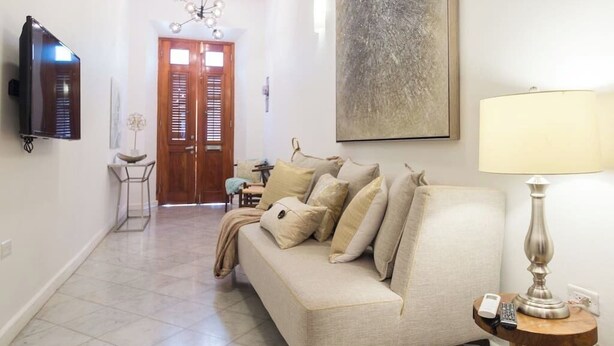 A living room with a sofa, a TV, a lamp, and a painting on the wall. - 152 Sol by Stay with Bear (San Juan)