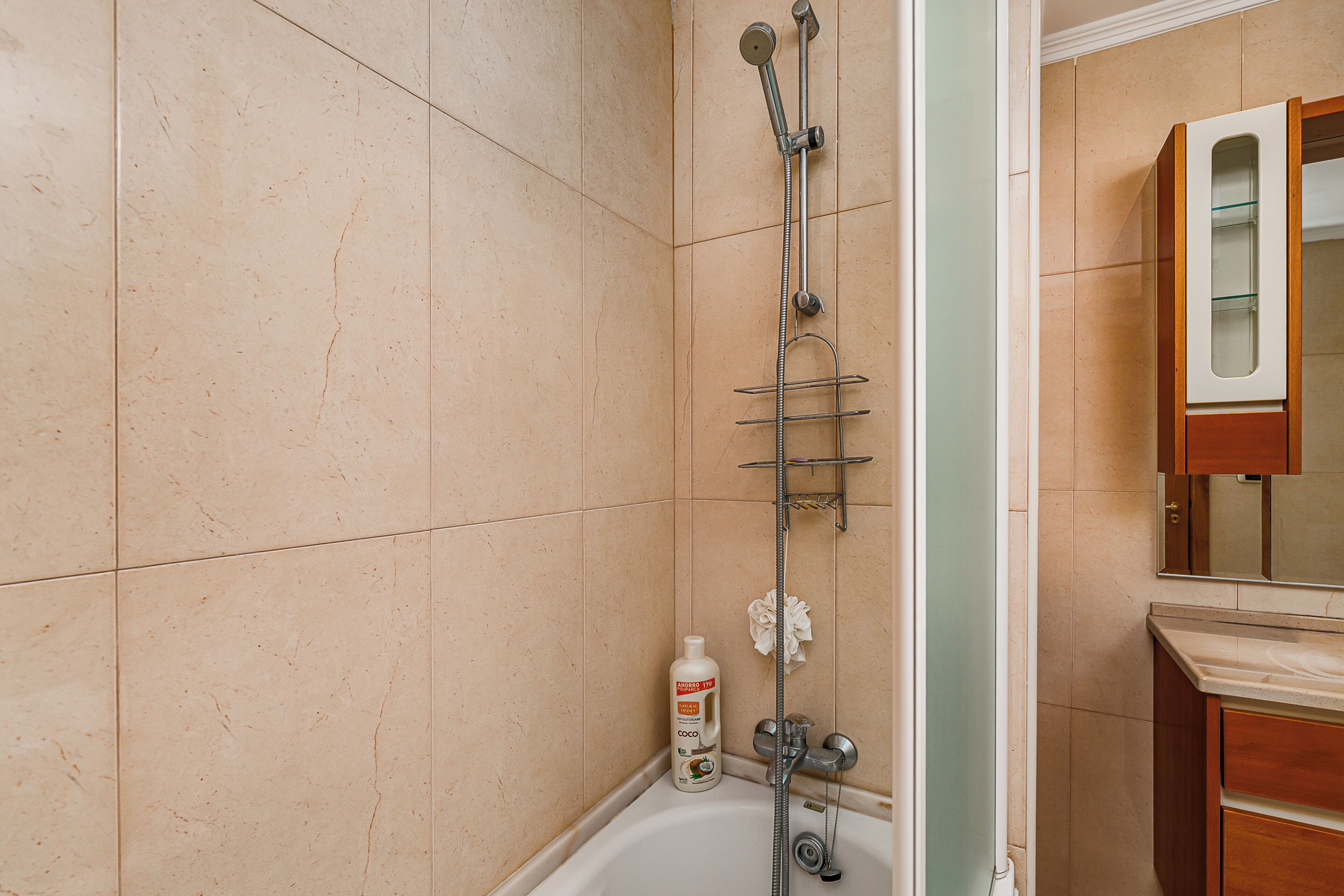 A bathroom with a bathtub, a shower, and a wooden cabinet with a mirror.