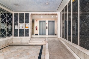 A lobby with marble flooring, a fire extinguisher, and two elevators. - Lisbon Easy Stay (Lisbon)