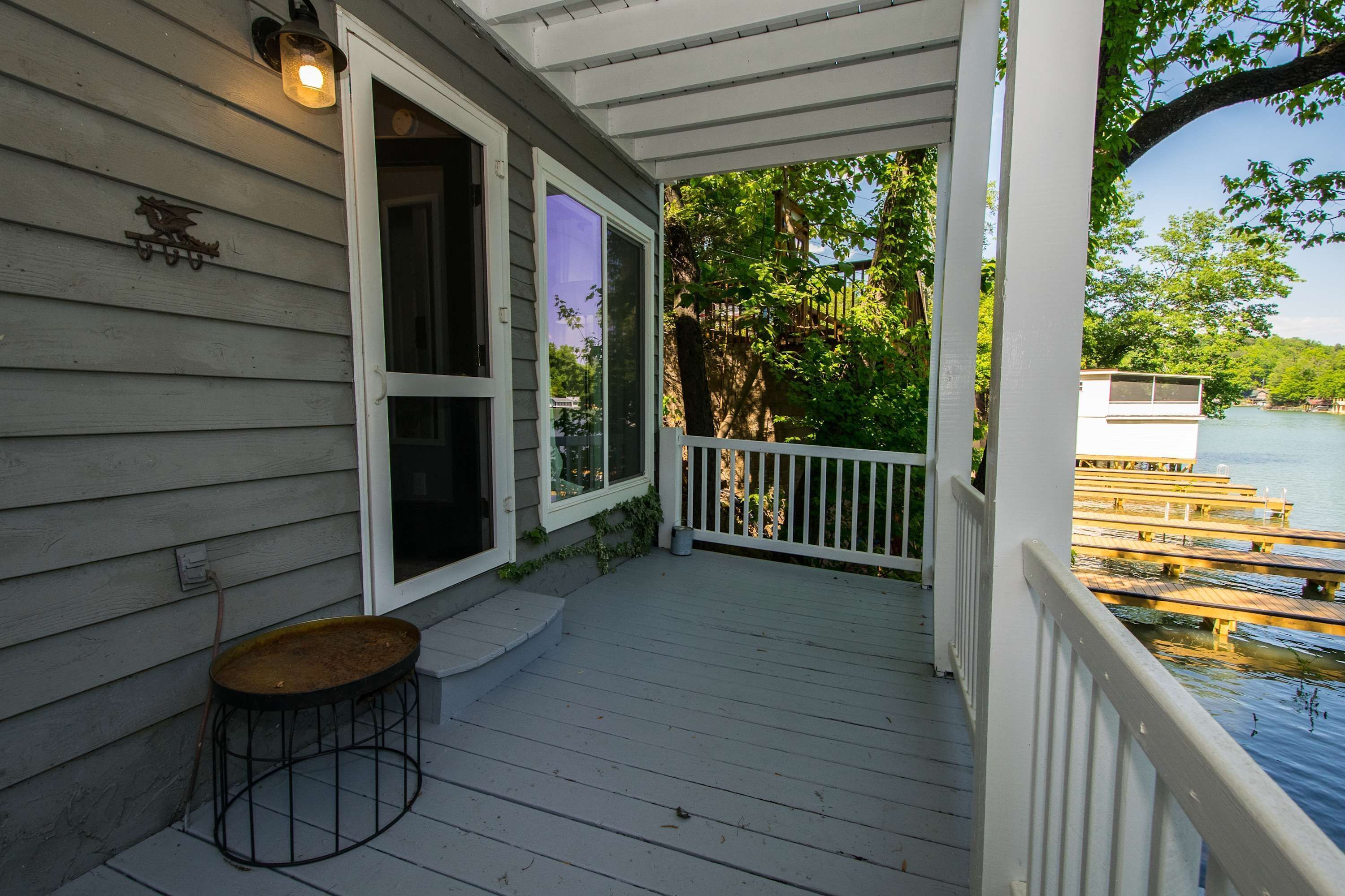 A wooden deck with a railing, a small table, and a view of a dock and water.