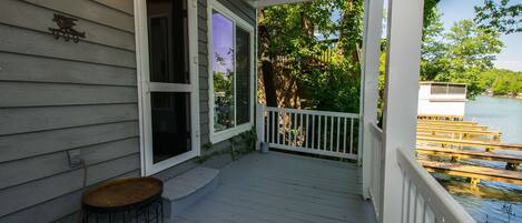 A wooden deck with a railing, a small table, and a view of a dock and water.