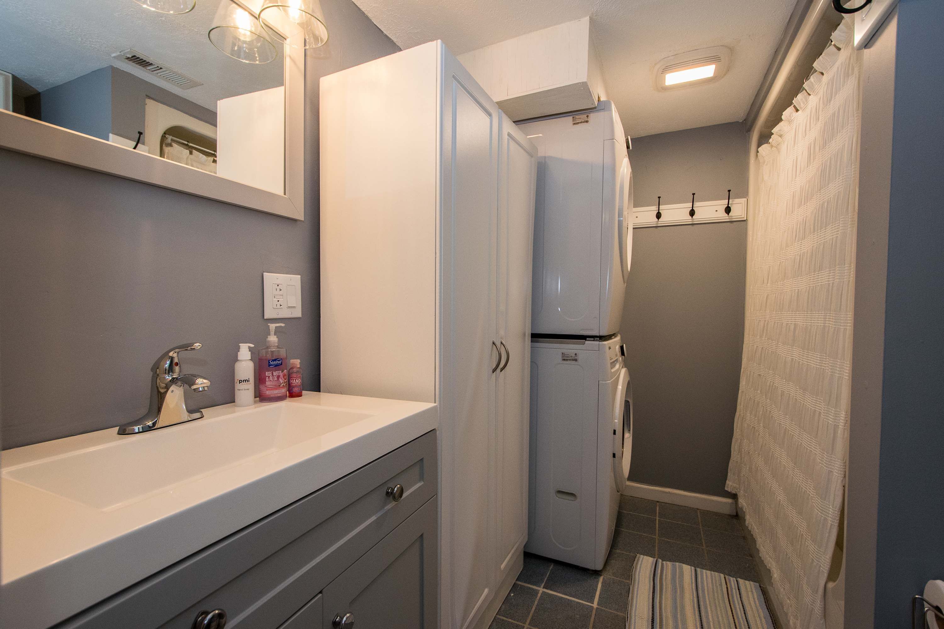 Une salle de bain compacte avec un lavabo blanc, un miroir et un petit réfrigérateur.