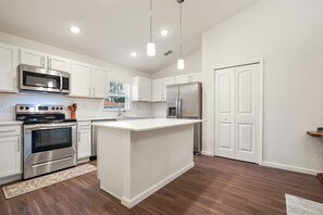 A modern kitchen with white cabinetry, stainless steel appliances, and a central island. - Coastal Vibes & Family Fun-Spacious 3BR, Kids Zone (Palm Coast)
