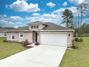 A single-story house with a garage, a front door, and a small porch area. - Coastal Vibes & Family Fun-Spacious 3BR, Kids Zone (Palm Coast)
