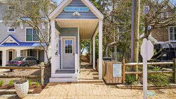 A small beach house with a covered porch, a sign reading 'Middlesex Beach,' and a wooden fence.