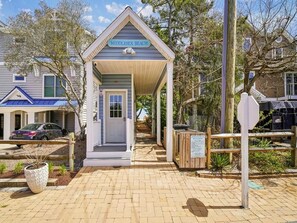 A small beach house with a covered porch, a sign reading 'Middlesex Beach,' and a wooden fence. - Coastal 6BR House w/ Pool & Decks | Beach Nearby! (Bethany Beach)
