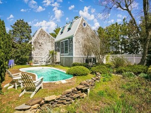 A two-story house with a swimming pool, surrounded by a stone wall and greenery. - Coastal 6BR House w/ Pool & Decks | Beach Nearby! (Bethany Beach)