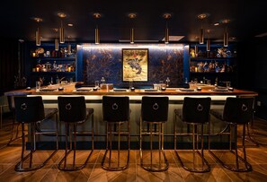 A bar area with a central island, bar stools, and a large framed artwork.