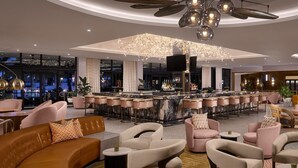 A modern bar area with a curved ceiling, bar stools, and a seating area with sofas and chairs. - PGA National Cottage | Pool, Spa & PGA Golf (Palm Beach Gardens)