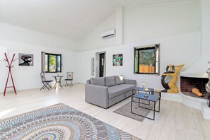A modern living room with a grey sofa, a patterned rug, a fireplace, and artwork on the walls. - Villa Taxiarchis by Corfuescapes  (Corfu)
