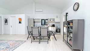 A modern kitchen with a dining area, white walls, and a clock. - Villa Taxiarchis by Corfuescapes  (Corfu)
