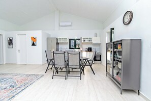 A modern kitchen with a dining area, white walls, and a clock. - Villa Taxiarchis by Corfuescapes  (Corfu)