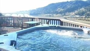 A hot tub with a view of a bridge and hills. - Rogue River Landing Resort (Gold Beach)