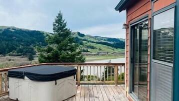 Una terraza de madera con un jacuzzi, con vistas a un paisaje montañoso.