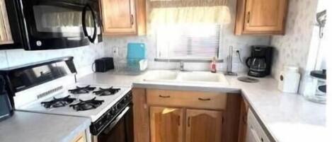 Cocina compacta para casa rodante con estufa, microondas y lavamanos.
