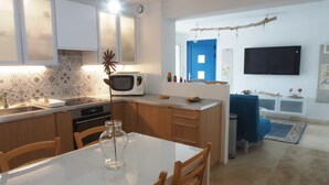 A modern kitchen with a dining area, white cabinets, a microwave, and a blue door. - Apartment ❤️ quiet and air-conditioned, sea on foot in 7 min! (carqueiranne)