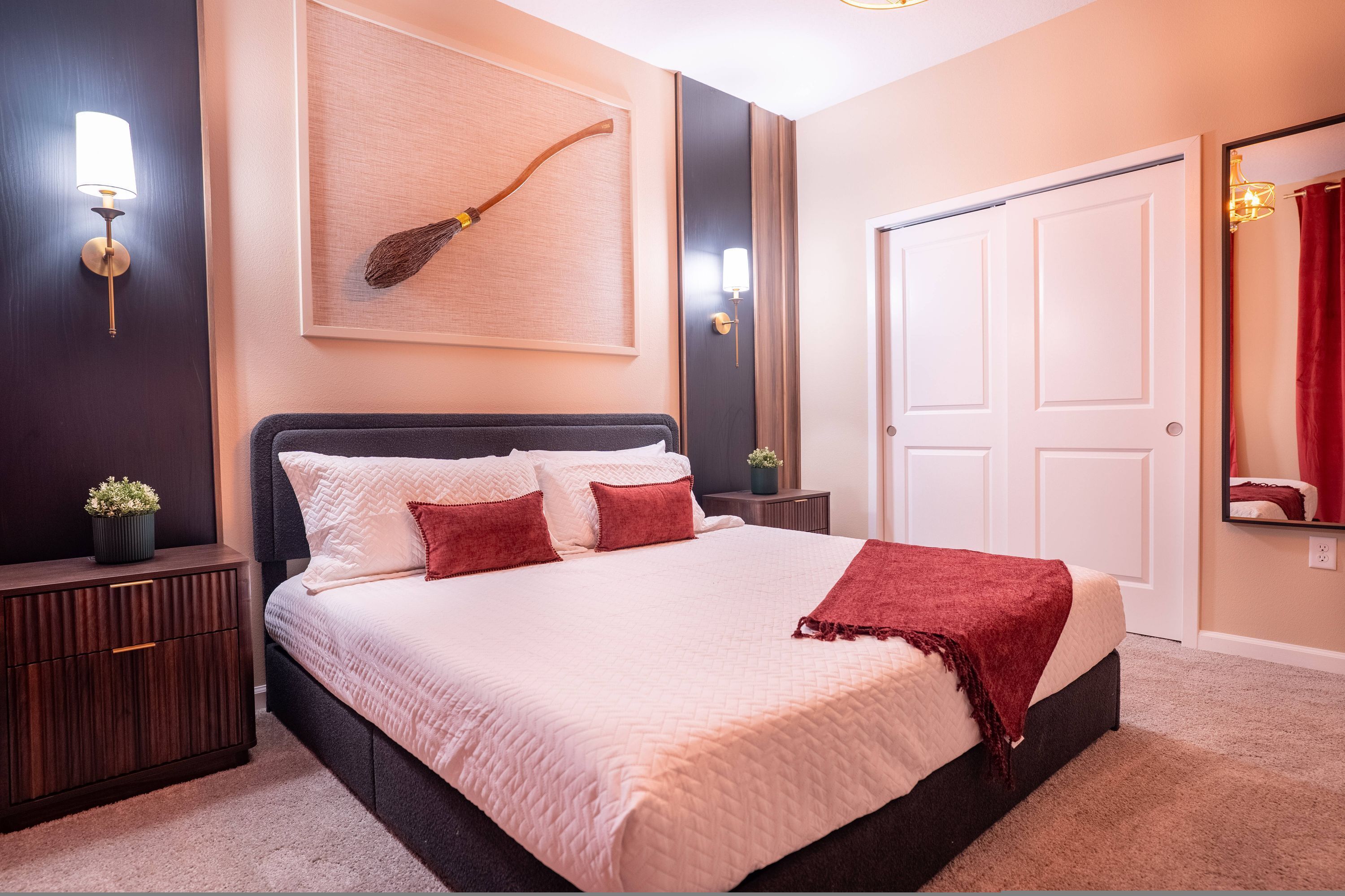 A neatly arranged bedroom with a large bed, bedside tables, a wall-mounted lamp, and a door.