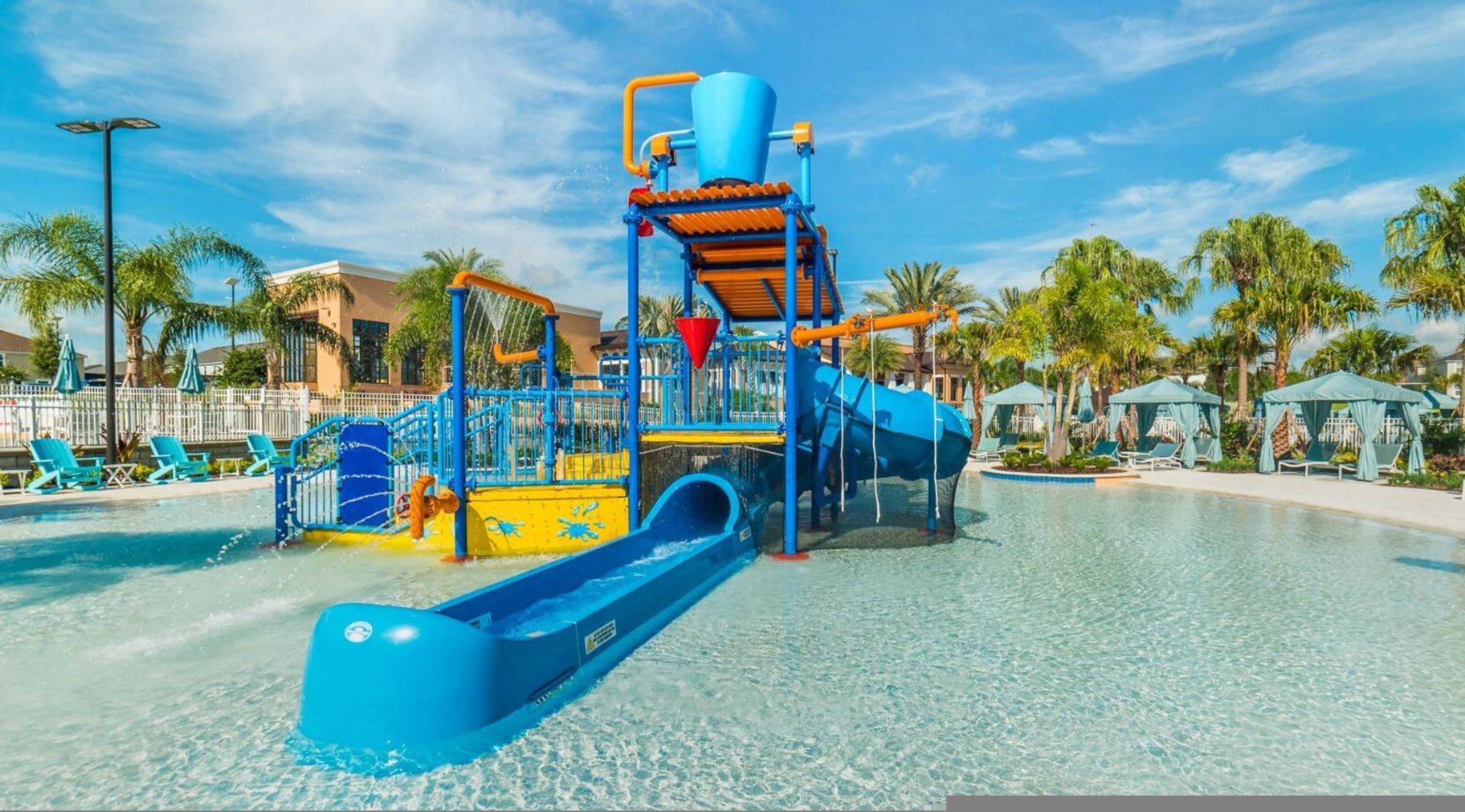 A water park with a blue slide, a water play structure, and a pool area.