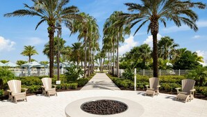 A pathway lined with palm trees, outdoor seating, and a circular fire feature. - 8BR Home With Pool Theater at Solara Resort (Kissimmee)