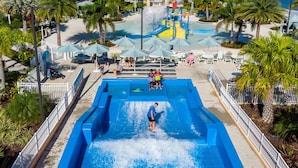 A water park with a large pool, slides, and palm trees. - 8BR Home With Pool Theater at Solara Resort (Kissimmee)