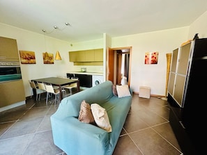 Ein modernes Wohnzimmer mit einer Couch, einem Esstisch und einer Küchenzeile.