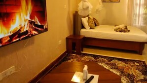 Ein Hotelzimmer mit einem Bett, einem an der Wand montierten Fernseher, einem Nachttisch und einem gemusterten Teppich.