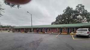 A motel with a green roof, multiple rooms, and a parking lot.