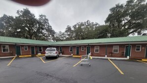 A motel with a green roof, brick exterior, and a parking lot with marked spaces.