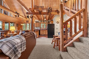 A log cabin interior with a living room, kitchen, and staircase. - Rustic Ridge Cabin 105 - Private Woodland Retreat near Devil's Lake (Merrimac)