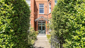A narrow pathway leading to a building with a green door and a small porch. - Bright & Modern Hampstead Apartment (London)