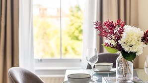 A dining table with a vase of flowers, a wine glass, and a bowl. - Bright & Modern Hampstead Apartment (London)