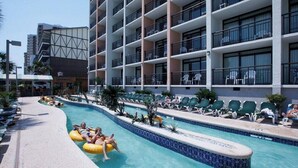 A hotel with a swimming pool, lounge chairs, and a building with multiple balconies. - Caribbean Resort Unit 732 (Myrtle Beach)