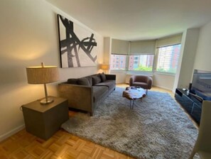 A modern living room with a sofa, a coffee table, a lamp, and a painting on the wall.