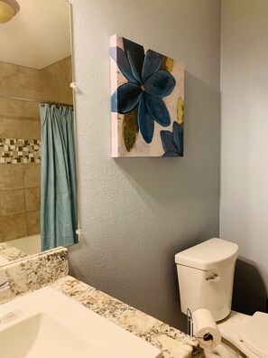 A bathroom with a toilet, sink, and shower curtain. - Perfect 3-bedroom house with AC in peaceful Baytown (Baytown)