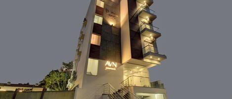 Un edificio moderno con un llamativo letrero de 'AVN COMFORTS', varios balcones y una escalera que conduce a la entrada.