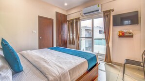 A bedroom with a bed, a TV, an air conditioner, and a window with curtains. - AVN Comforts Mysore (Mysore)
