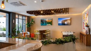 A modern reception area with a curved counter, seating, and artwork on the walls. - Stay Americana district in Guadalajara near La Minerva & Chapultepec (Guadalajara)