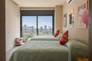 A bedroom with a city view, two beds, a large window, and decorative pillows. - Stay Americana district in Guadalajara near La Minerva & Chapultepec (Guadalajara)