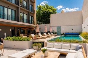 A rooftop pool area with lounge chairs, a sofa, and umbrellas. - Stay Americana district in Guadalajara near La Minerva & Chapultepec (Guadalajara)