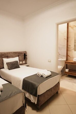 A bedroom with a bed, bedside tables, a nightstand, a bathroom with a toilet and sink. - Hotel Abedini (Sarandë)