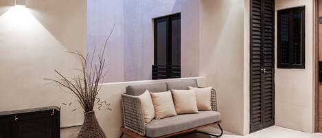 A modern interior with a sofa, a wicker vase, and a door with shutters.