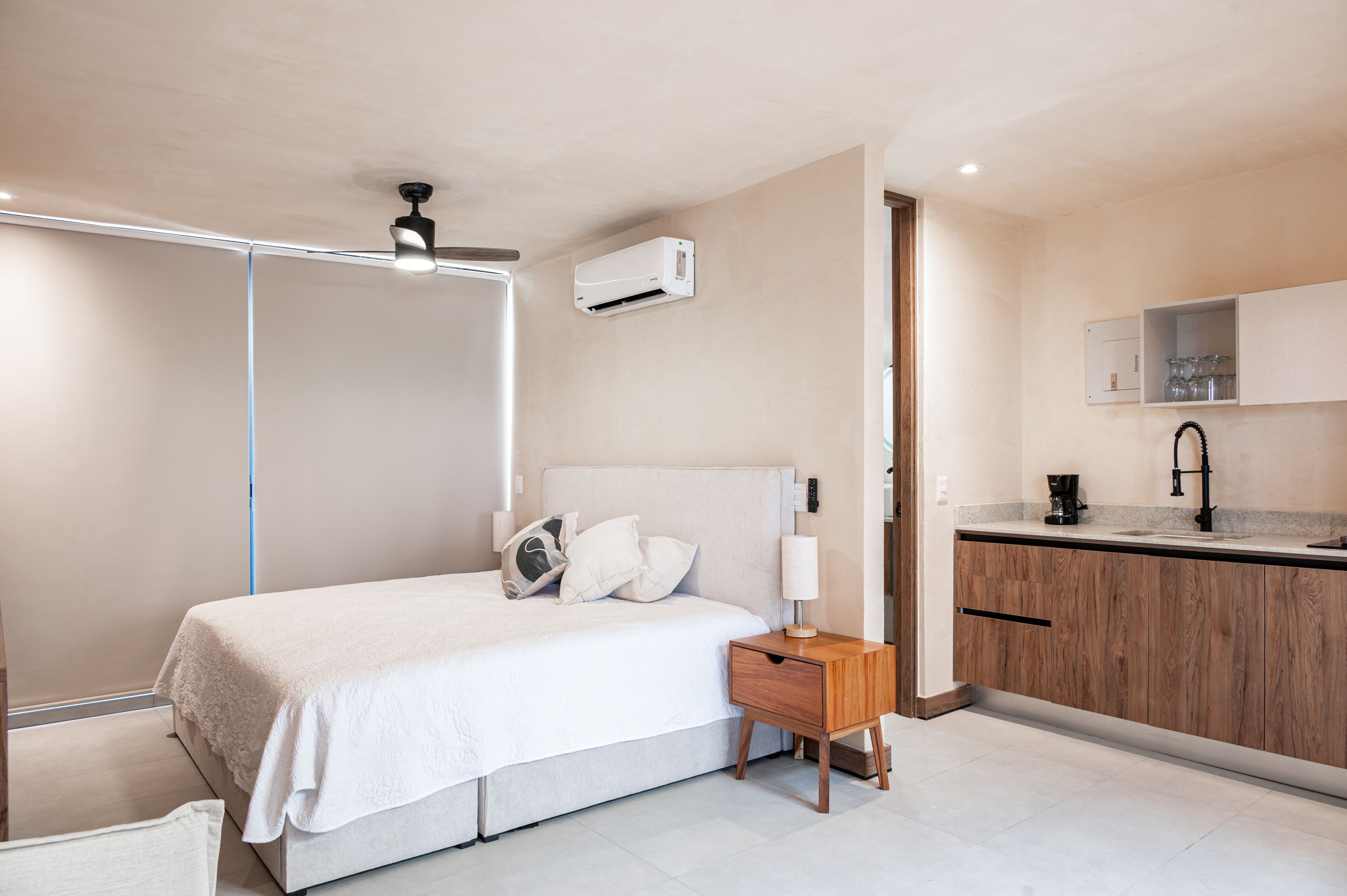 A bedroom with a bed, bedside table, nightstand, and a ceiling fan.